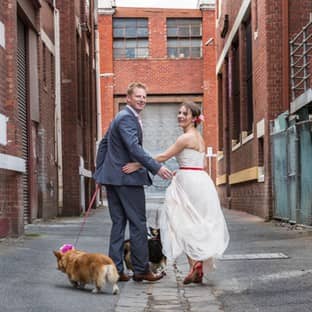 Happy couple with dog celebrates wedding in urban alleyway.